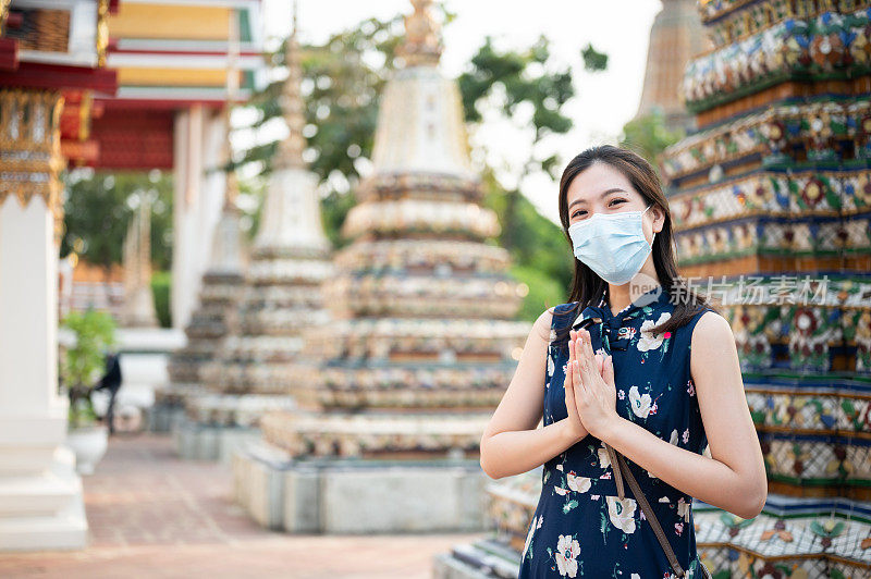 笑容灿烂的亚洲游客在泰国曼谷wat arun temple旅游，她戴着面罩保护下午2.5点的污染，用酒精清洁手保护covid-19冠状病毒